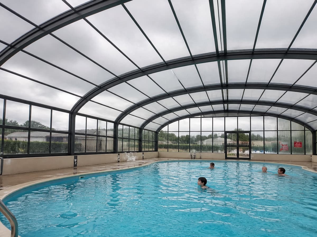 Piscine intérieure couverte avec toit vitré, nageurs dans l